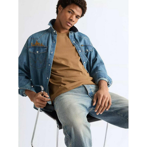 Model Wearing Wrangler Men's Retro 1980s Oversized Denim Western Shirt with Embroidery in Trail Blazer Blue - Sat in Chair