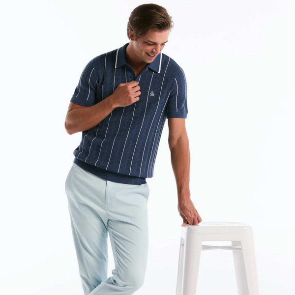 Model Leaning on Chair Wearing the Original Penguin Men's Mod Vertical Mesh Stripe Polo Shirt in Sargasso Sea