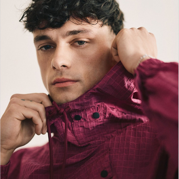 Lifestyle photo of man wearing Weekend Offender Grohl Overhead Men's Ripstop Hooded Jacket in Kirsch