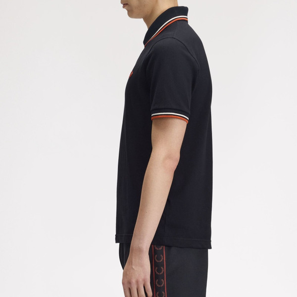 Model Wearing Fred Perry M12 Twin Tipped Polo Shirt in Black, Tramline White and Summer Clay - Side On