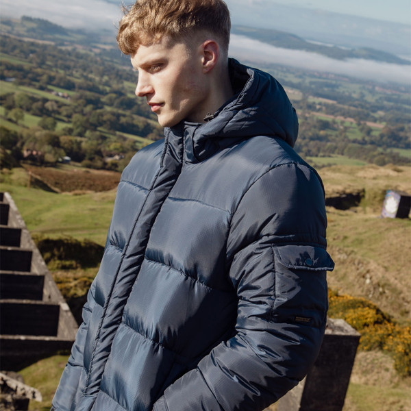 Side view of man wearing Luke 1977 Inuit Men's Long Hooded Puffer Jacket in Porpoise Blue