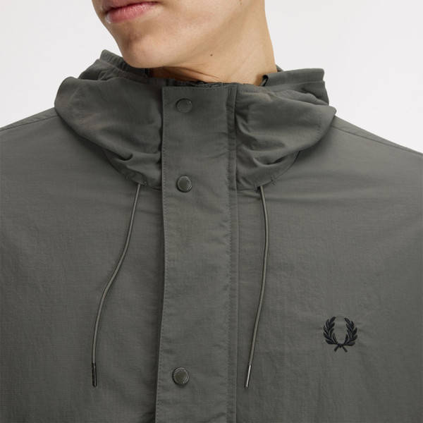 Model Wearing Fred Perry Cropped Ripstop Hooded Parka Jacket in Field Green - Close up laurel wreath