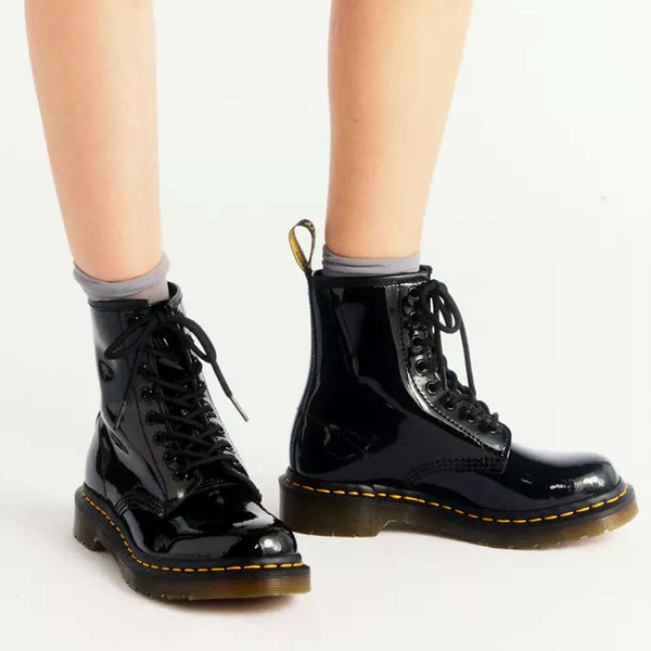 Woman wearing Dr Martens Women's 1460 Patent Lamper 8 Eye Leather Boots in Black