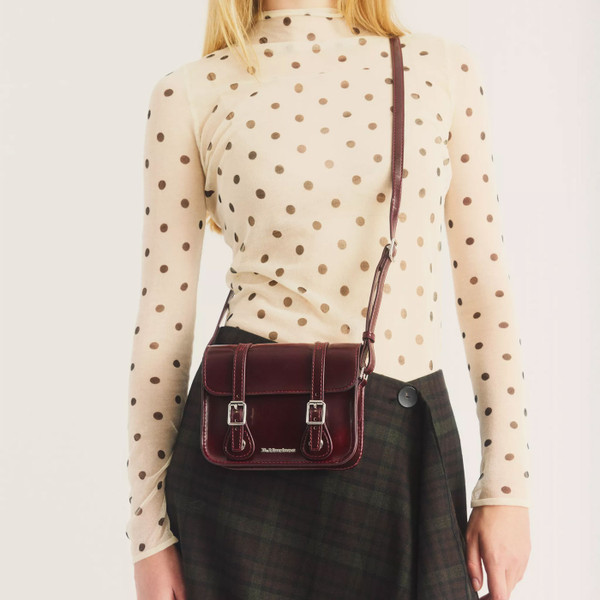 Woman wearing Dr Martens 7 Inch Vegan Faux Leather Crossbody Satchel Bag in Cherry Red