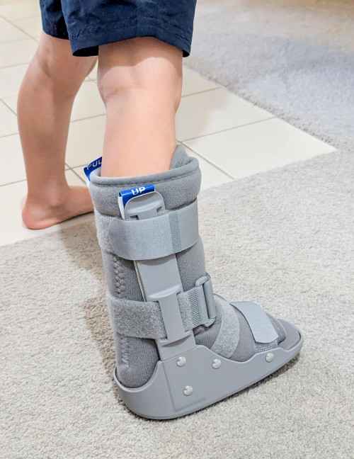 Child walking while wearing paediatric fracture boot, demonstrating ankle and foot support during rehabilitation.