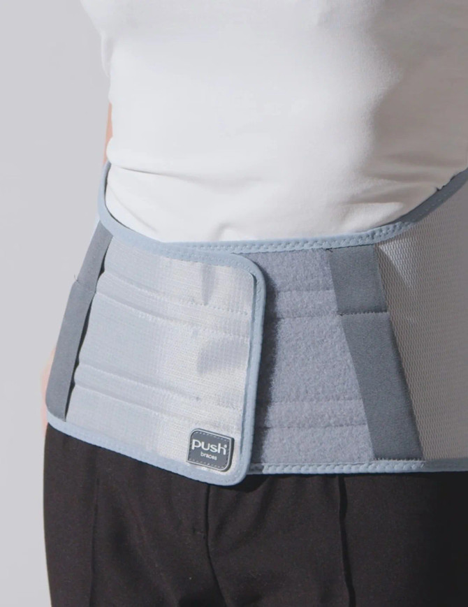 Discreet Push care Back Brace worn under clothing, offering comfortable lumbar support for everyday activities and work.