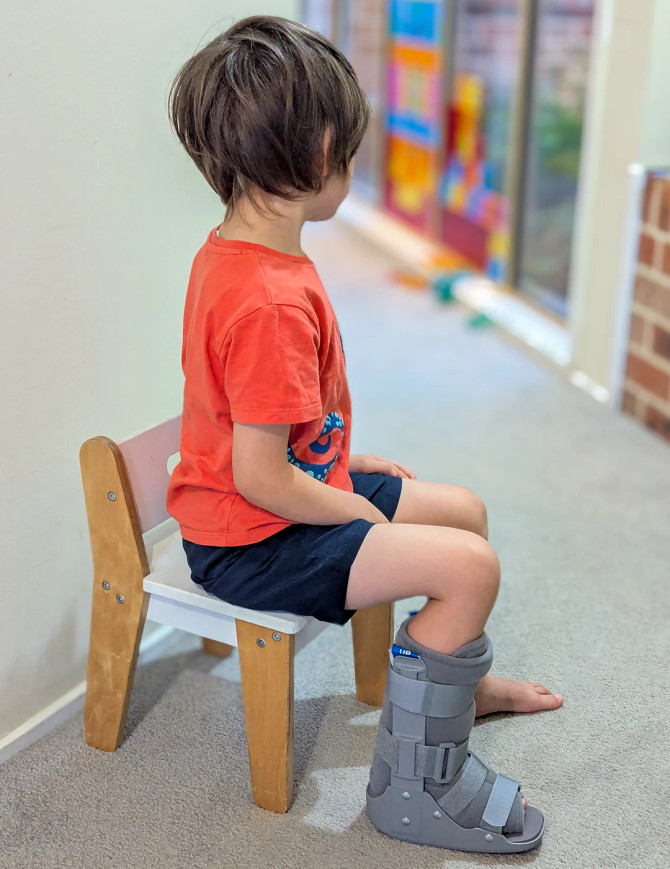 Lifestyle image of child wearing medical walking boot for recovery from foot or ankle injury.