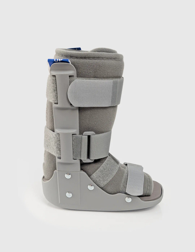 Side profile of paediatric walking boot displaying supportive frame and rocker sole design for controlled mobility.
