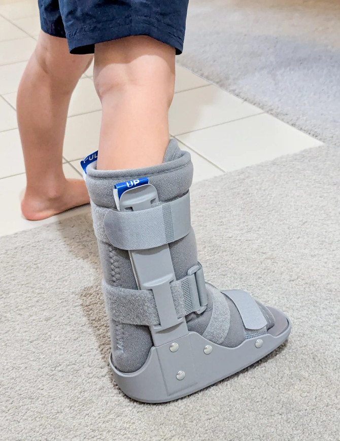 Child walking while wearing paediatric fracture boot, demonstrating ankle and foot support during rehabilitation.