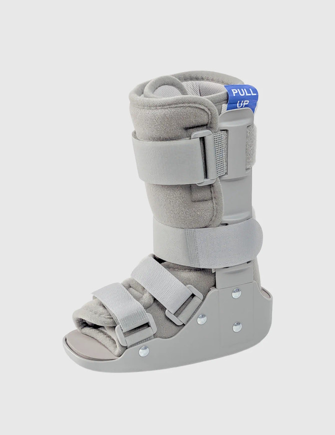 Product-only side view of paediatric walker boot showing adjustable straps, rigid support frame, and cushioned lining.