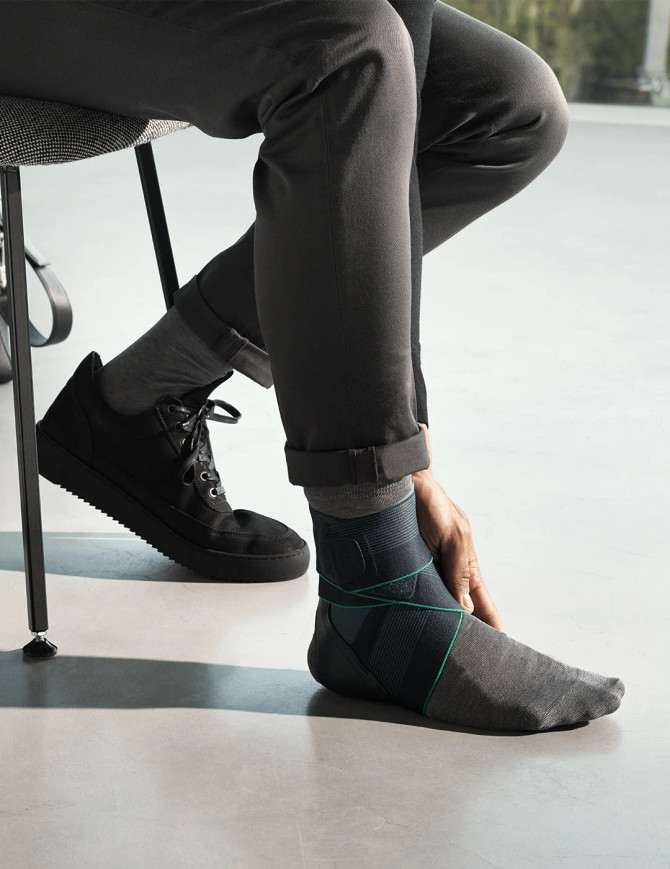 Seated lifestyle image showing Push med ankle brace worn with footwear for daily activity and rehabilitation use.