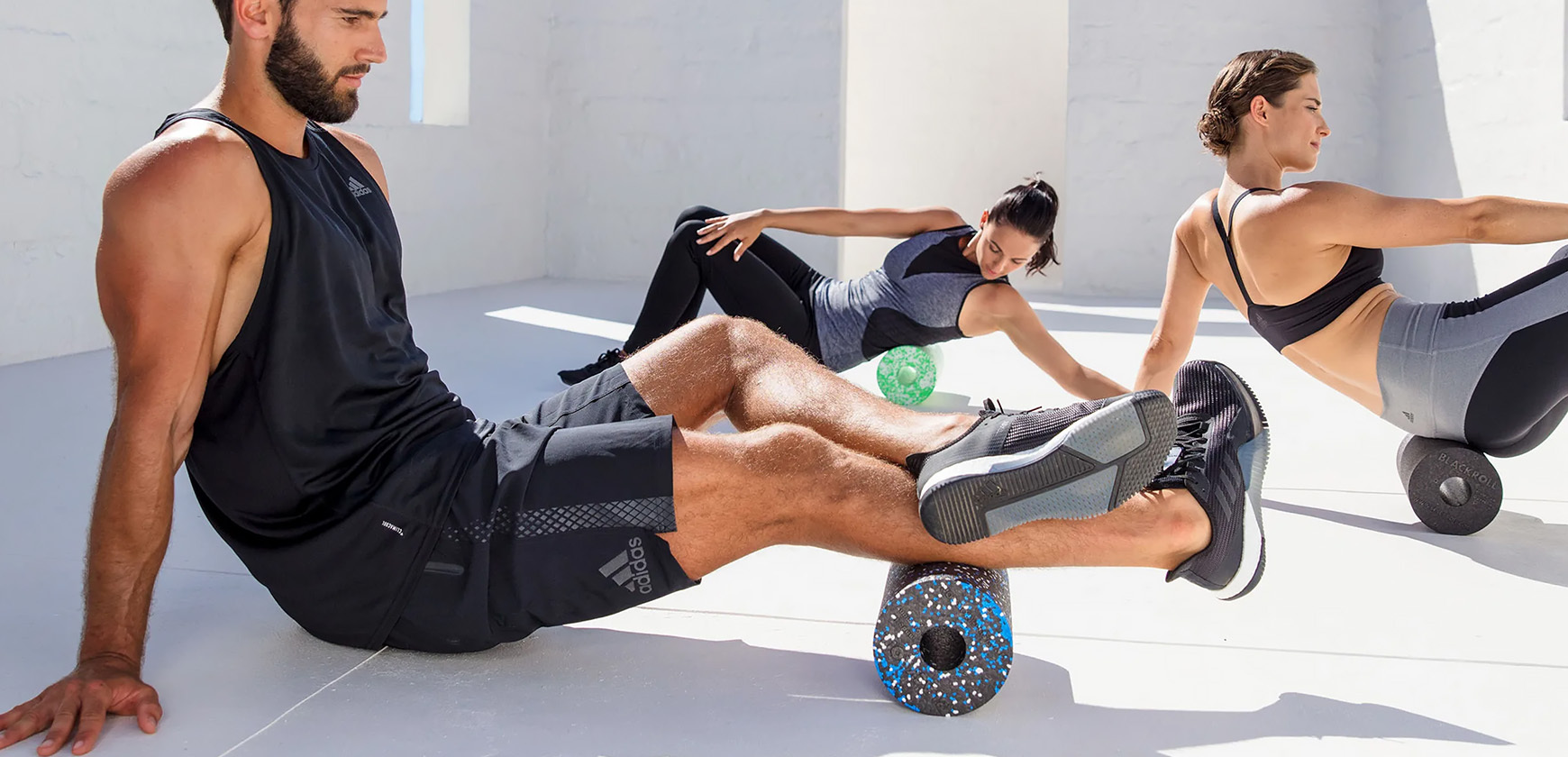 People using BLACKROLL foam rollers doing various exercises.