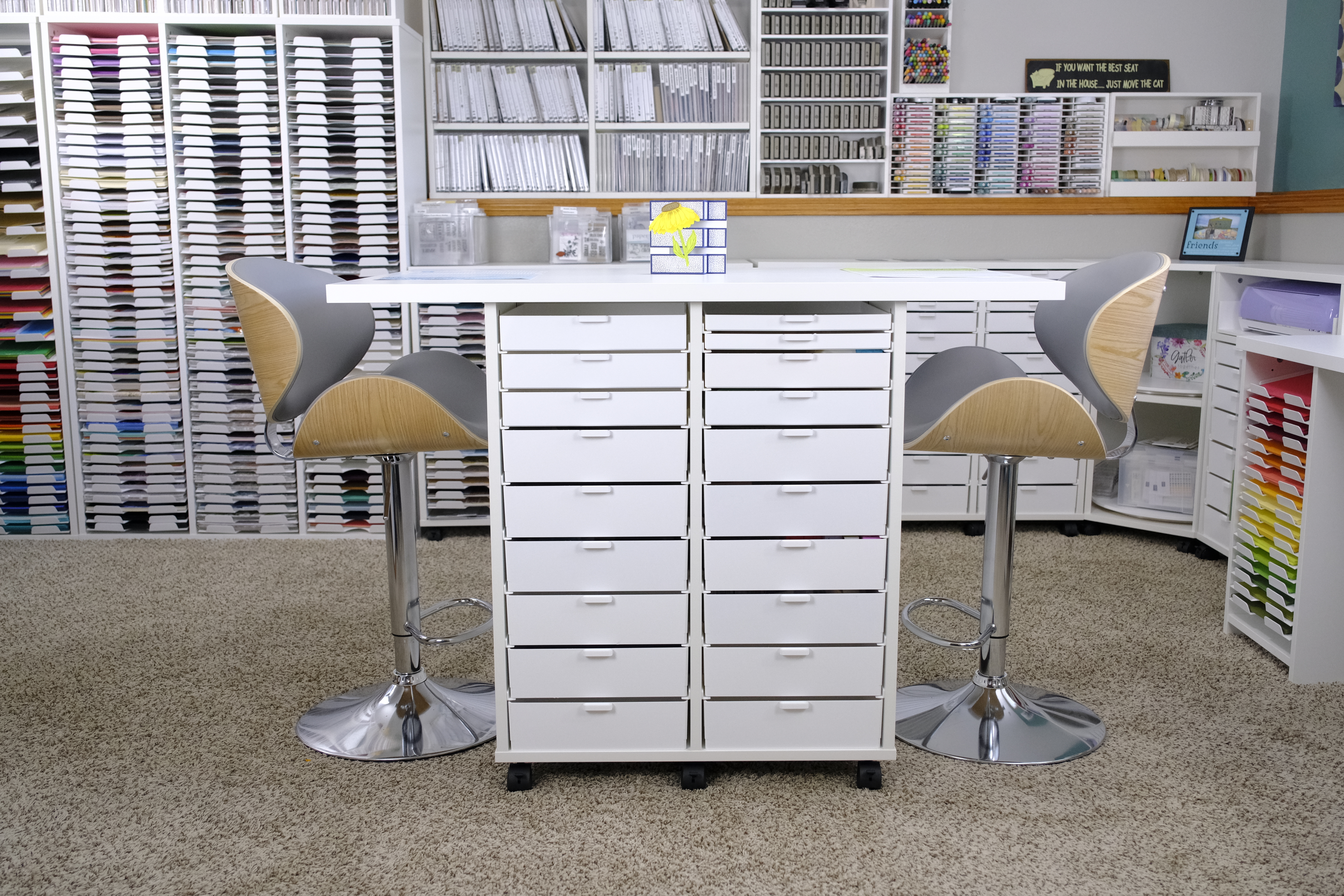 A fully coordinated craft room with matching white storage, a center work island, and seating