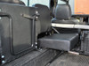 Britpart Rear Inward Facing Single Seat Black Vinyl for Defender (1986-2016) | DA4067, interior view of a black vinyl single seat installed in the rear of a vehicle with a metal grille barrier.