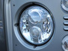 Britpart Lynx Eye LED Headlamp Pair Right Hand Drive 7 Inch Round DOT & E-Marked - DA6282 for Defender, close-up of the modern LED headlamp with a shiny, reflective surface and multiple LED bulbs inside the round casing. Britpart Lynx Eye LED Headlamp Pair Right Hand Drive 7 Inch Round DOT & E-Marked - DA6282 for Defender, close-up of the modern LED headlamp with a shiny, reflective surface and multiple LED bulbs inside the round casing.