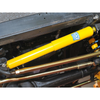 Britpart SUPER GAZ Steering Damper for Defender, yellow steering damper installed in a vehicle's suspension system.