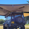 Vehicle mounted 270 degree awning creating shaded camping and working area