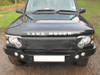 Britpart Radiator Muff Black for Discovery 2 (2002-2004 Facelift Models) | DA2162, front view of a black Land Rover Discovery 2 SUV with radiator muff installed on the grille and hood.