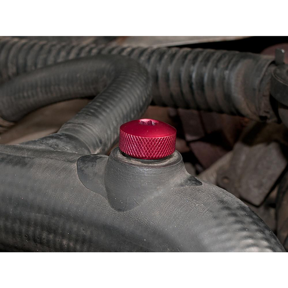 Britpart Top Coolant Hose Bleed Screw Red Aluminium for Defender Td5, close-up of the red aluminium bleed screw on a vehicle's radiator hose.