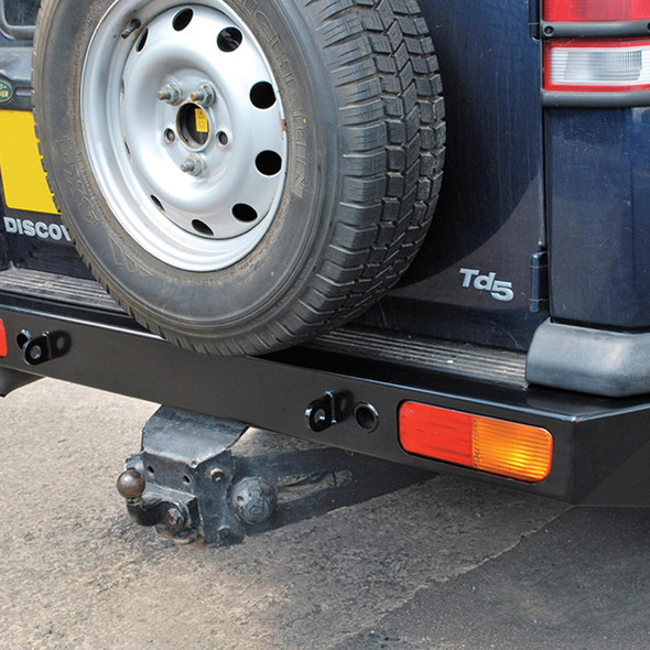 Britpart Heavy-Duty 4mm Steel Rear Bumper for Discovery 2, black steel bumper attached to the rear of a vehicle with a spare tire mounted above it.