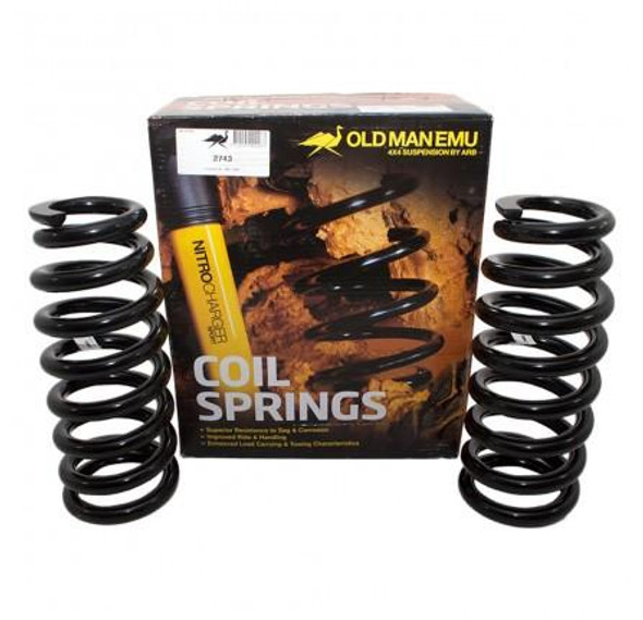 Old Man Emu OME Discovery 3 OME Front Coil Springs Plus 50mm Medium Load, black coil springs with packaging box in the background. Old Man Emu OME Discovery 3 OME Front Coil Springs Plus 50mm Medium Load, black coil springs with packaging box in the background.