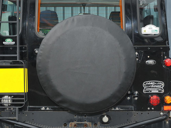 Britpart Plain Black Vinyl Spare Wheel Cover - DA2027, on the rear of a Land Rover Defender, protecting the spare wheel.