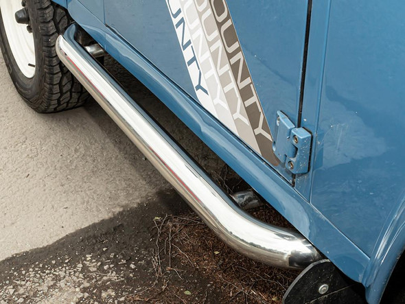 Britpart Stainless Steel Side Step for Defender 90, close-up view of a shiny stainless steel side step mounted on a blue Land Rover Defender 90.