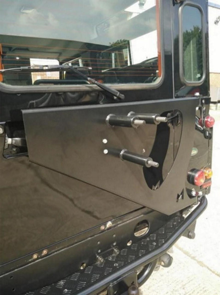 Terrafirma Swingaway Spare Wheel Carrier for Defender, mounted on the rear of a vehicle, with a black metal finish and mechanical components for securing a spare wheel.