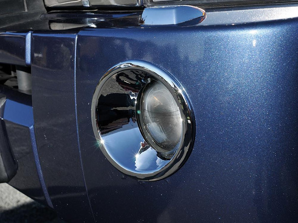 Britpart Chrome Fog Lamp Surround Bezels for Discovery 3, close-up of the shiny chrome fog light bezel on a dark blue vehicle. Britpart Chrome Fog Lamp Surround Bezels for Discovery 3, close-up of the shiny chrome fog light bezel on a dark blue vehicle.