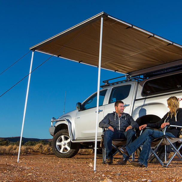 ARB 4X4 Accessories Expedition Side Awning ARB - DA6828, outdoor vehicle awning providing shade for camping with two people sitting under it in a desert setting.