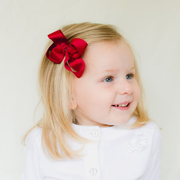 Little girl with a cranberry Adelynn toddler bow on a velvet gator no-slip clip for fine hair