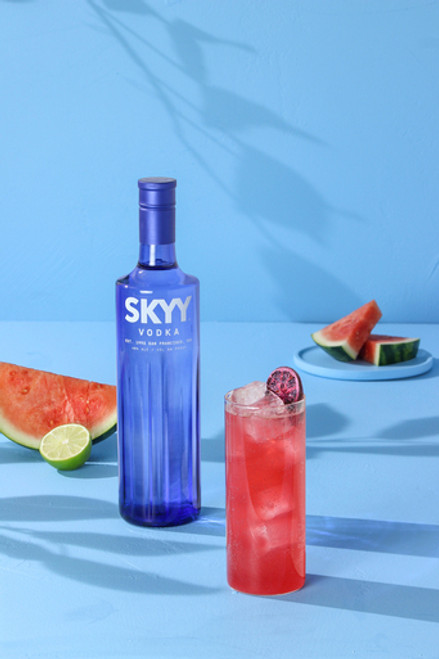 intriguing magenta hued cocktail in a collins glass with a hibiscus lime wheel on a blue background