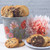 Metal poppy bucket filled with 18 freshly baked, individually wrapped gourmet cookies in assorted flavors, vibrant keepsake container perfect for thoughtful gifting and brightening any occasion.