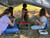 Campers making pine needle baskets under a shelter they built