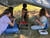 Campers making pine needle baskets under a shelter they built