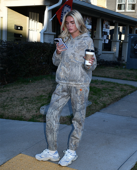 Woman wearing Banded Realtree Xtra Grey camo hoodie and joggers outdoors.