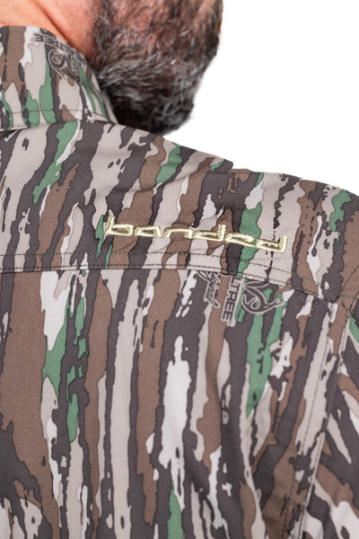 Close-up of embroidered branding on shoulder of Banded Men’s Badlander camo hunting shirt.