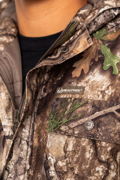 Detail of Realtree APX logo and chest pocket on camo parka.