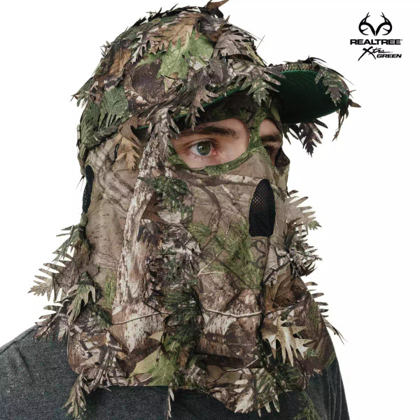 A Realtree Xtra Green QuikCamo leafy ball cap is shown with the mask pulled down, featuring vibrant natural-green foliage and mesh ventilation.