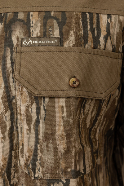 Close-up of the Men's Milk River Button Down Camo Shirt’s chest pocket, featuring button closure and Realtree branding.