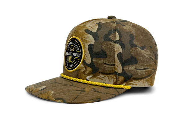 Side view of a micro-suede camo rope hat featuring a round Realtree Established patch and yellow rope detail main.