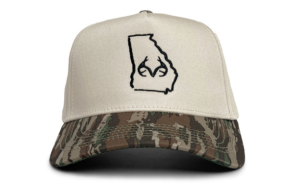 Front view of a cream hybrid cap with a black Georgia state outline and antler logo, featuring a Realtree Original camo bill main.