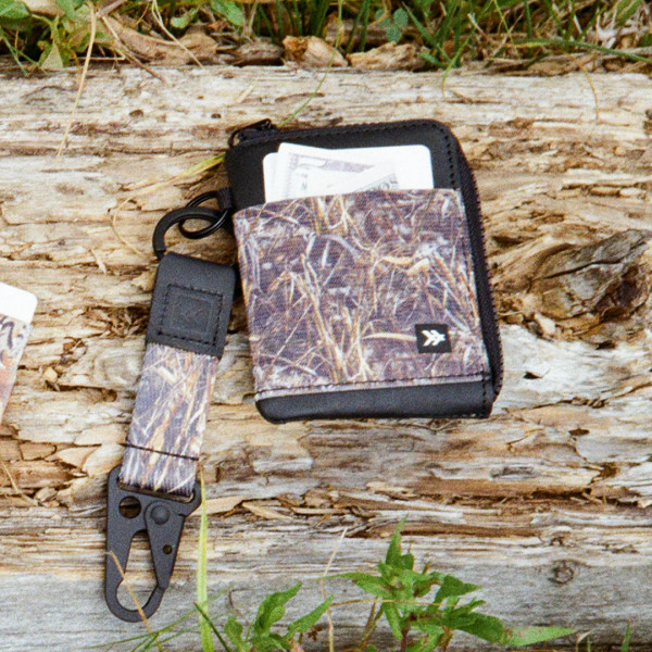 Thread Realtree MAX-7 camo zipper wallet shown outdoors with matching key clip accessory on wooden surface.