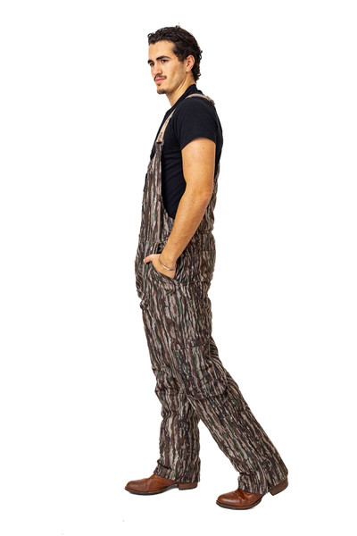 Realtree Original insulated hunting bibs shown from the side, highlighting the full-length camo pattern, relaxed fit, and side hand pockets.