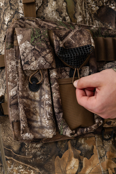 Close-up of side storage pockets and call holders on Realtree APX turkey vest.