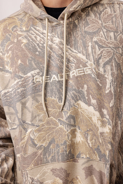 Close-up of Realtree logo embroidery on faded camo hoodie chest.