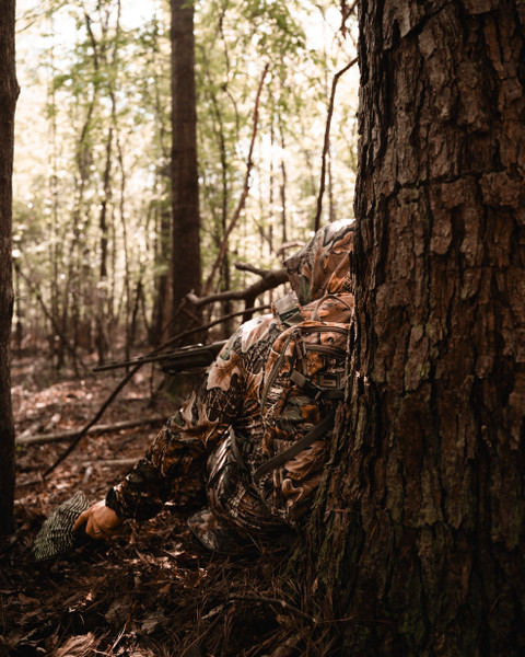 Hunter sitting against tree wearing Banded Air Elite camo turkey vest.