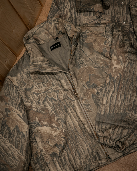 Close-up of Banded Bonfire camo puffer jacket fabric and zipper detail in Realtree Xtra Grey.