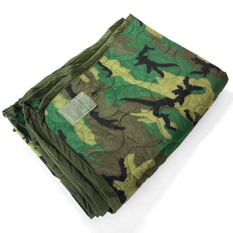 Folded US military woodland camo poncho liner (woobie) with quilted stitching and olive trim