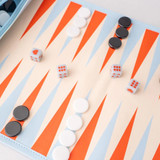 Game board featuring backgammon design being used with circular plastic game pieces and dice
